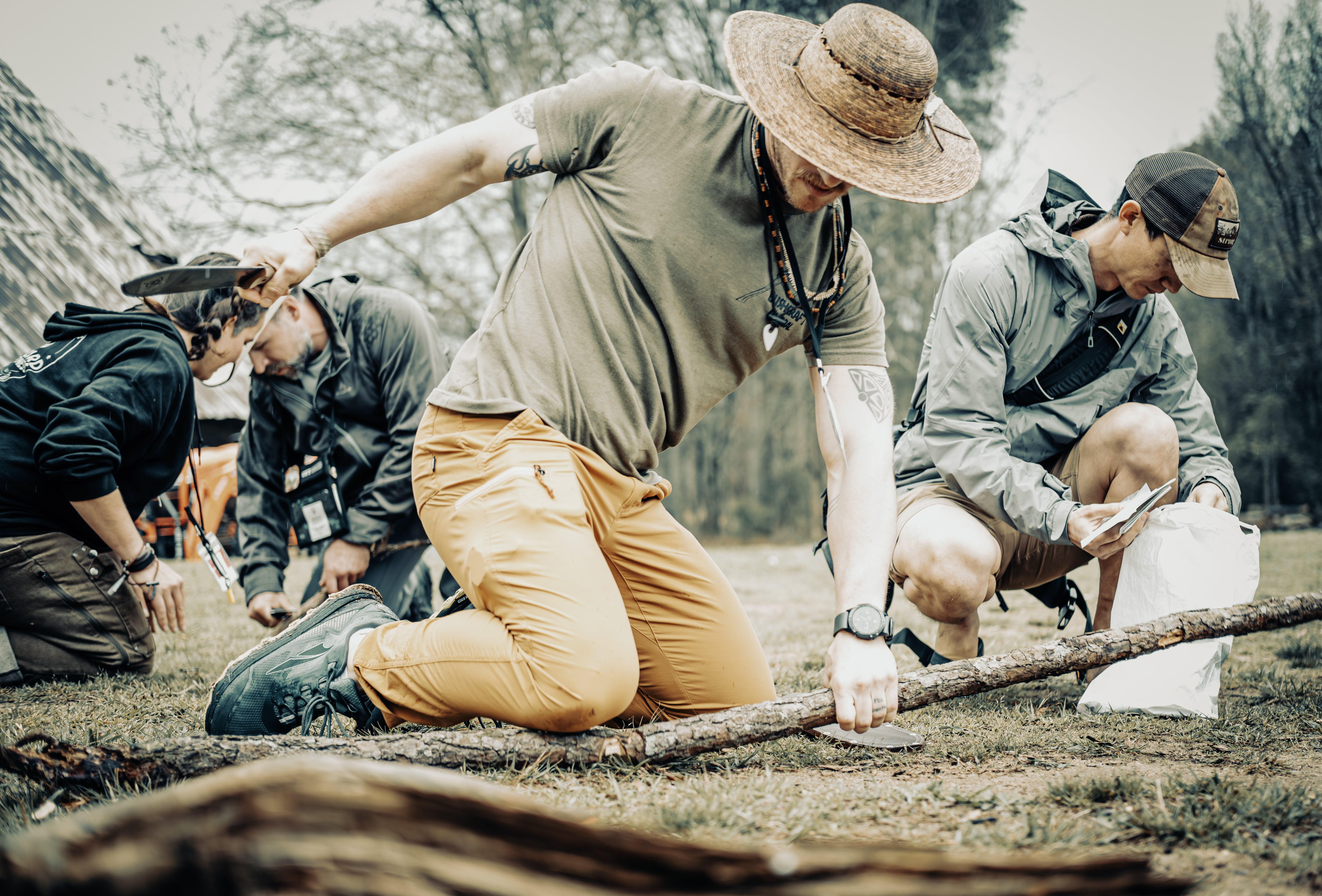 Group of people outdoors, possibly setting up a camp or engaging in nature activity.