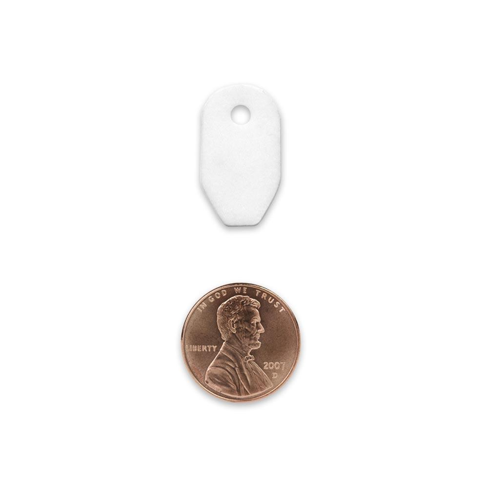 white ceramic striker with hole for paracord or other cordage shown in comparison to the size of the penny that is similar size