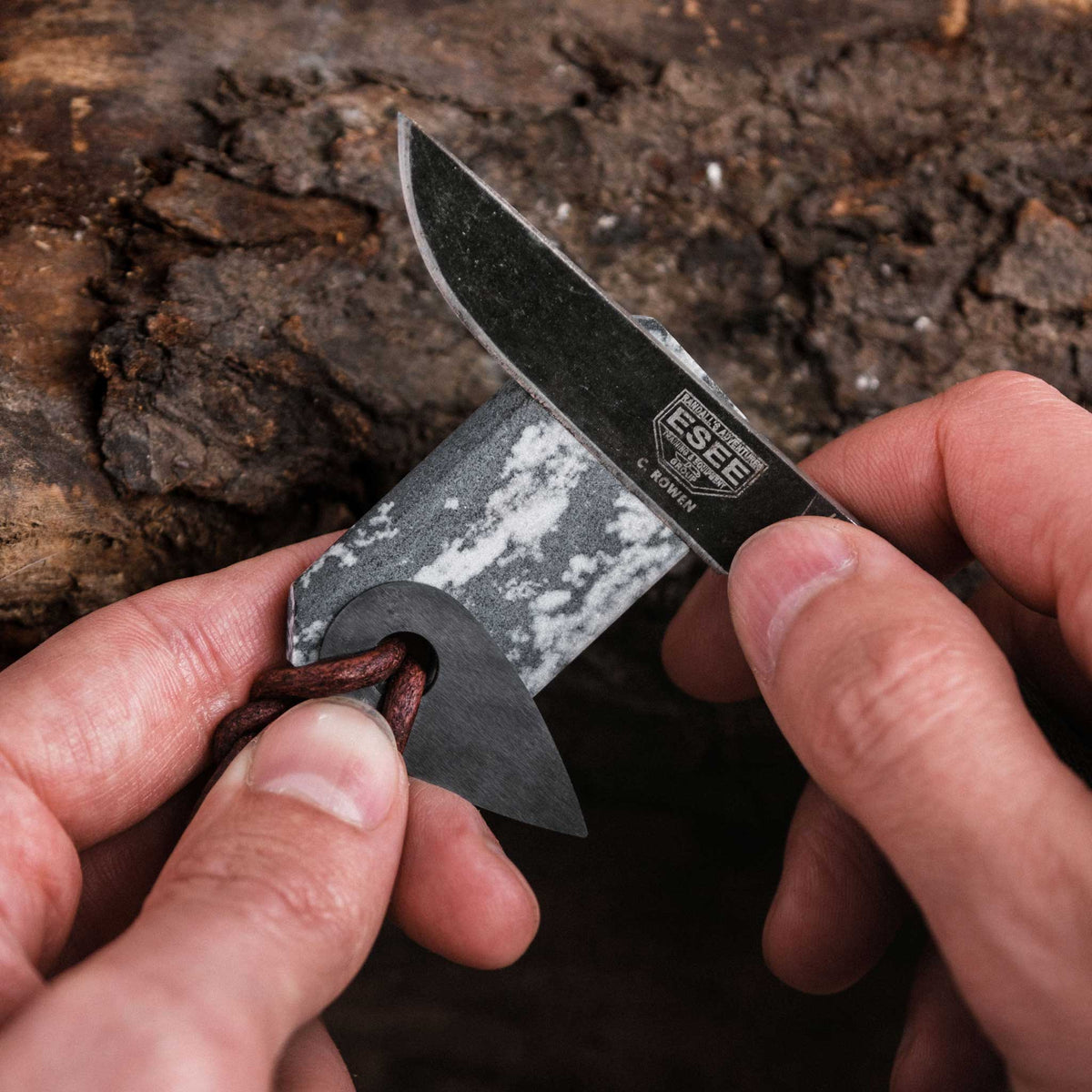 Using the back side of the novaculite whetstone pendant to sharpen a knife blade with the spark ceramic rotated to the side