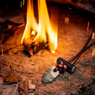 Bushcraft necklace with black ceramic shown with a fire on a stump