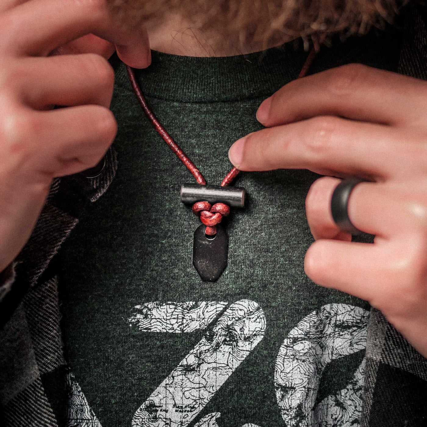 Black ceramic bushcraft necklace by Wazoo shown worn on a male with green shirt